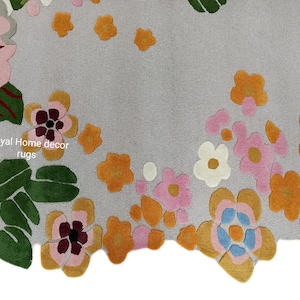 May include: A gray rug with a floral design. The rug features large, colorful flowers in shades of pink, orange, yellow, and white, with green leaves. The text "Royal Home decor rugs" is visible.