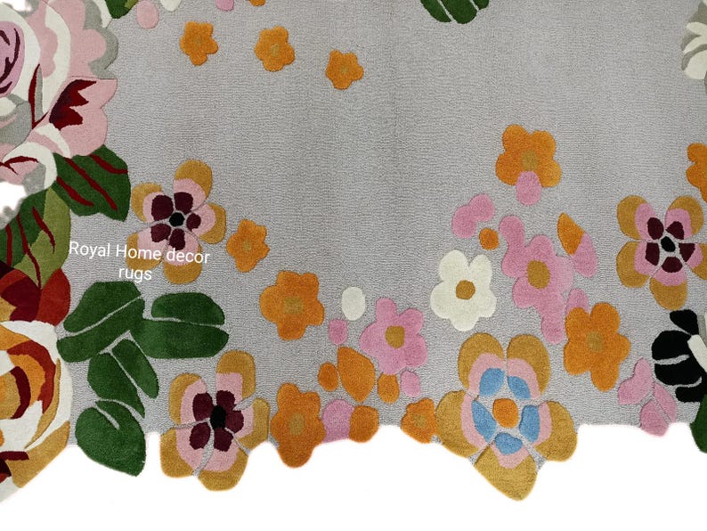 May include: A gray rug with a floral design. The rug features large, colorful flowers in shades of pink, orange, yellow, and white, with green leaves. The text "Royal Home decor rugs" is visible.