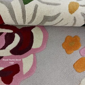 May include: Close-up of two floral rugs. The top rug features white, green, and gray floral designs. The bottom rug has pink, red, and orange floral patterns. The text "Royal Home decor rugs" is visible.