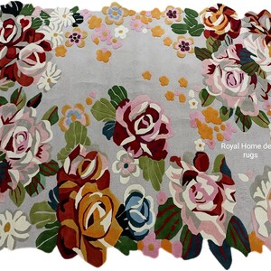 May include: A rectangular rug with a light gray background and a floral design. The rug features large roses in shades of red, pink, and yellow, with green leaves. Smaller flowers in pink, white, and orange are scattered throughout the design. The text "Royal Home decor rugs" is visible.