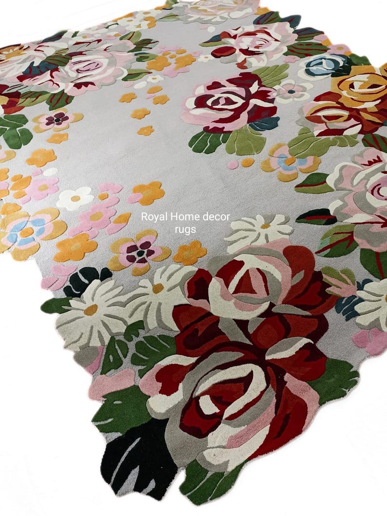 May include: A floral area rug with a light gray background and a colorful pattern of roses and other flowers. The rug features shades of red, pink, yellow, and green. The text "Royal Home decor rugs" is visible.
