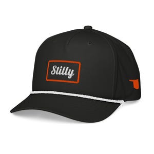 May include: Black baseball cap with a white rope detail and a curved brim. The cap features the word "Stilly" embroidered in white on a rectangular patch with an orange border. An orange state outline is on the side.