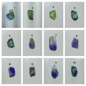 May include: A collection of twelve raw, uncut gemstones arranged in a grid, numbered one through twelve. Each stone displays unique colour variations including shades of blue, green, violet, and clear, with irregular, jagged, and crystalline textures.