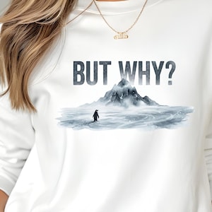 Könnte beinhalten: Weißes Sweatshirt mit dem Text "BUT WHY?" über einer Aquarellillustration eines Pinguins in einer verschneiten Landschaft mit einem Berg im Hintergrund. Das Design ist in Grau- und Blautönen gehalten.