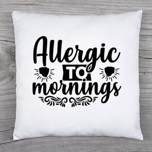 May include: White square pillow with the text "Allergic to mornings" in black script. The design includes stylized sunbursts and decorative flourishes, creating a playful and relatable statement for home decor.