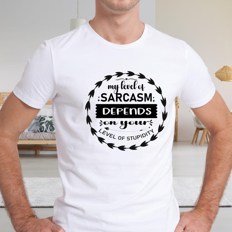 May include: White t-shirt with a black graphic that reads "my level of sarcasm depends on your level of stupidity." The text is inside a circular wreath design.