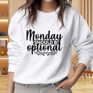 May include: White sweatshirt with the text "Monday should be optional" in a black, stylized font. The text is centered on the chest, with decorative flourishes beneath the word "optional". The sweatshirt has long sleeves and a crew neck.