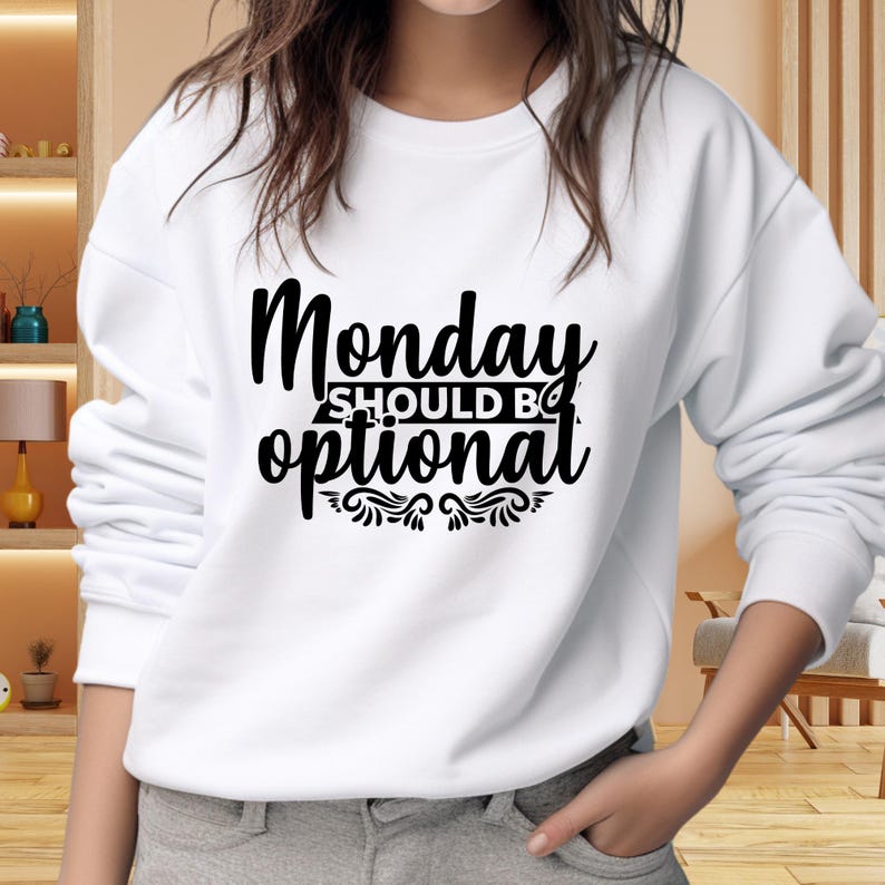 May include: White sweatshirt with the text "Monday should be optional" in a black, stylized font. The text is centered on the chest, with decorative flourishes beneath the word "optional". The sweatshirt has long sleeves and a crew neck.