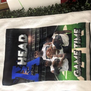 May include: White rectangular towel with a printed image of a football team. The image features players in white shirts and black caps, holding a football. The words "HEAD" and "GAME TIME" are printed on the towel.