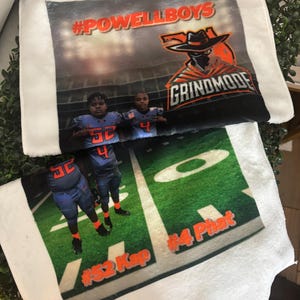May include: White plush towels with a football field design. One towel features the text "#POWELLBOYS" and a graphic of a masked cowboy. The other towel shows two football players on a green field with the text "#52 Kap" and "#4 Phat".