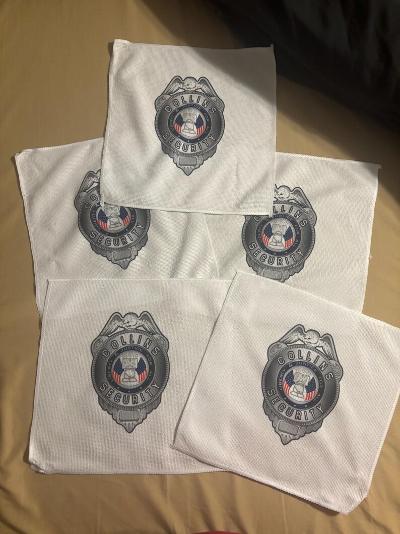 May include: Five white square cloths with a printed security badge design. The badge is silver with the words "COLLINS SECURITY" and a central emblem featuring a building and the words "LIBERTY & JUSTICE FOR ALL".
