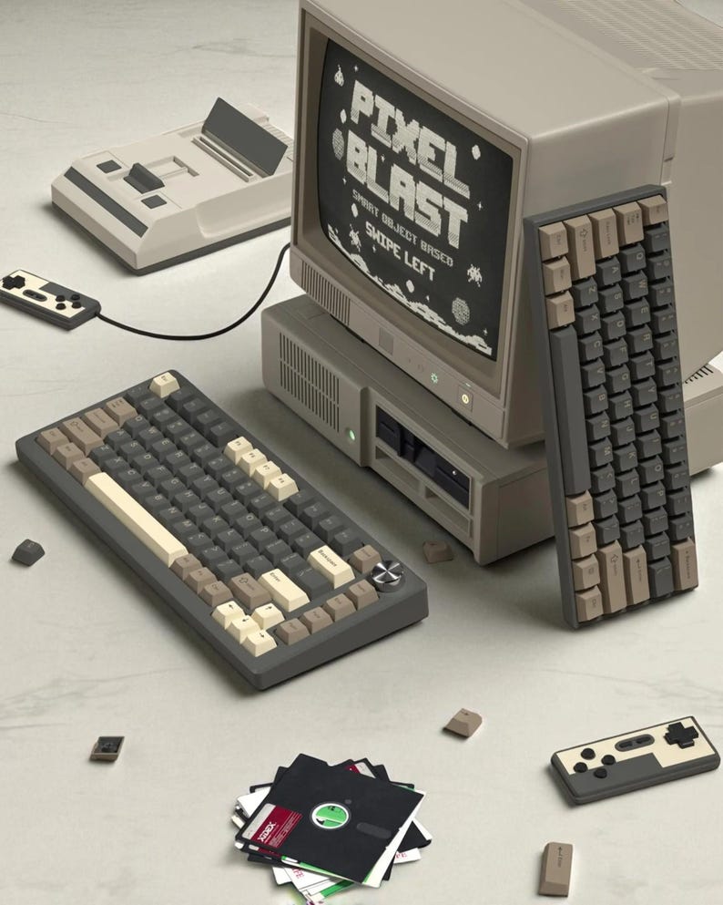 May include: A retro computer setup featuring a monitor displaying "Pixel Blast" text, two keyboards with gray, beige, and white keys, a game console, a controller, and floppy disks. The color scheme is primarily gray and beige.