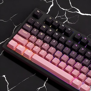 May include: A mechanical keyboard with a black frame and gradient keycaps. The keycaps transition from pink to purple, with white lettering. The keyboard has function keys and number keys. The background is a black marble surface.