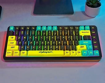 May include: A black and yellow mechanical keyboard with multi-coloured keycaps. The keyboard features the word "Cyberpunk" on the spacebar and has a variety of function keys. The keys are backlit with a rainbow effect.