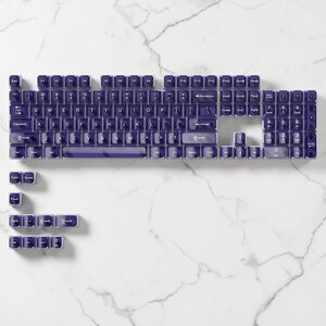 May include: A mechanical keyboard with purple keycaps, displayed in a disassembled state. The keycaps are laid out on a white marble surface, revealing the keyboard's structure. The keycaps are purple with white lettering.