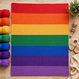 Könnte beinhalten: Eine rechteckige Häkeldecke mit horizontalen Streifen in einer Regenbogenfarbfolge aus Rot, Orange, Gelb, Grün, Blau, Indigo und Violett. Die Decke wird zusammen mit passenden Garnknäueln, einer Holzrassel und Babyschuhen präsentiert.