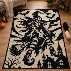 May include: A rectangular crochet rug featuring a black and cream graphic design of a witch flying on a broomstick against a large full moon. The scene includes silhouettes of bats, a spooky house, and bare tree branches in a high-contrast pattern.