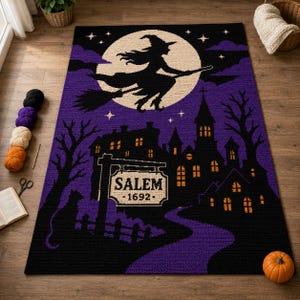 May include: A rectangular crochet rug featuring a black silhouette of a witch on a broomstick flying across a large cream moon. The design includes a dark purple sky, a black haunted house, a cat, and a sign that reads SALEM 1692 in black text.