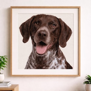May include: A framed print featuring a close-up of a German Shorthaired Pointer dog. The dog has brown and white speckled fur, with a pink tongue and brown eyes. The artwork is set against a cream background and framed in a light brown wooden frame.