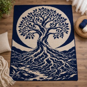 May include: A rectangular crochet blanket featuring a large, detailed tree of life design in cream against a deep navy blue background. The tree has intricate branches and exposed roots that extend across the lower portion of the textile.