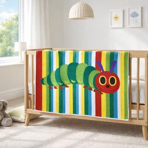 May include: A vibrant baby blanket with a caterpillar motif, displayed on a wooden cot. The blanket showcases vertical stripes in red, yellow, green, and blue. The caterpillar has a red head, green body segments, and purple antennae.
