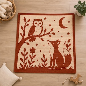 May include: A square crocheted blanket with a woodland design. It features an owl on a branch, a fox, a crescent moon, and stars, all in rust-coloured and cream yarn. The blanket has a rust-coloured border and is made of yarn.