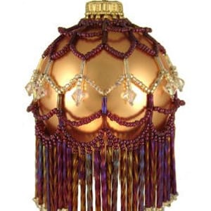 Puede incluir: Un adorno de vidrio dorado con flecos de cuentas color burdeos y dorado y un diseño de red de cuentas color burdeos y dorado.