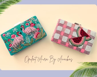 May include: Two beaded clutch purses. One is teal with pink flamingos and floral embroidery. The other is pink and white checkered with watermelon slices. The text "Opulent Aura By Anaikas" is in the image.