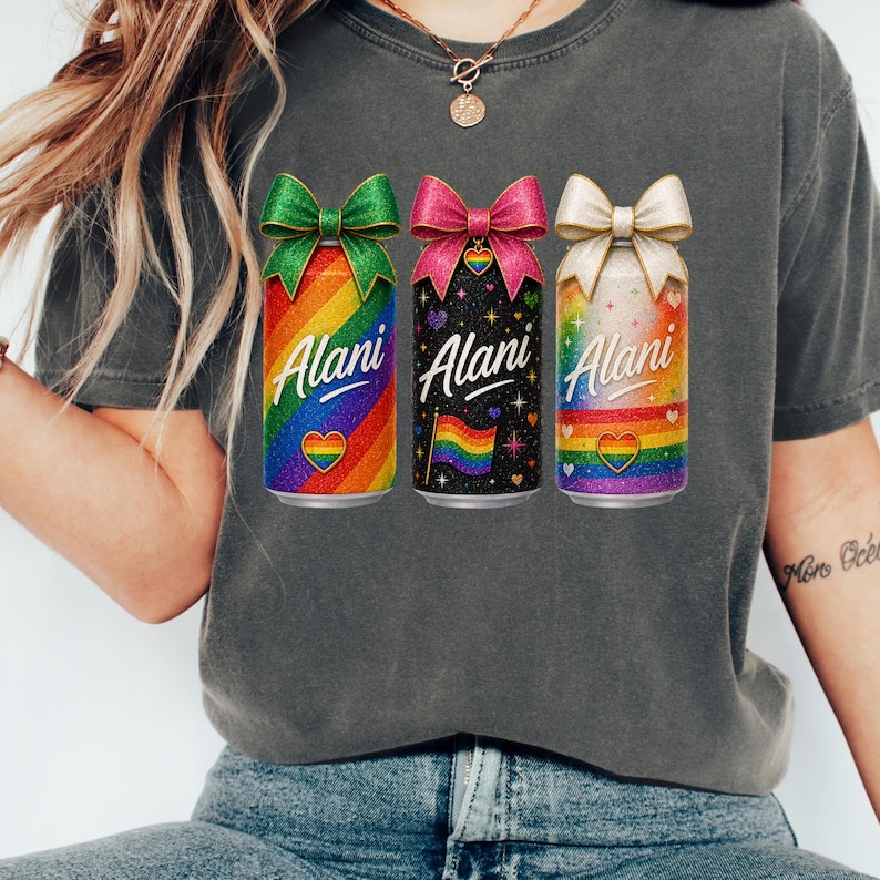Pu&ograve; includere: Una maglietta grigia con tre lattine colorate con fiocchi. Le lattine hanno disegni arcobaleno, neri e bianchi, con la parola "Alani" in corsivo. Ogni lattina ha un cuore arcobaleno e una bandiera arcobaleno.