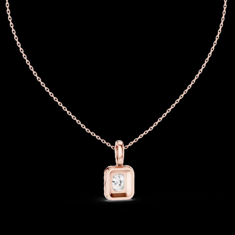 Może przedstawiać: Naszyjnik z r&oacute;żowego złota z kwadratową zawieszką z przezroczystym, kwadratowo oszlifowanym kamieniem szlachetnym. Zawieszka jest osadzona w oprawie z lunetą i wisi na delikatnym łańcuszku. Naszyjnik jest prezentowany na czarnym tle.