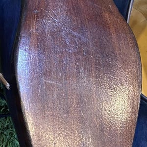 May include: The bottom sole of a dark brown leather shoe featuring a stacked heel and a smooth, polished finish. The sole is secured with a series of small, visible metal nails along the rounded toe and the arch, showing a classic construction.