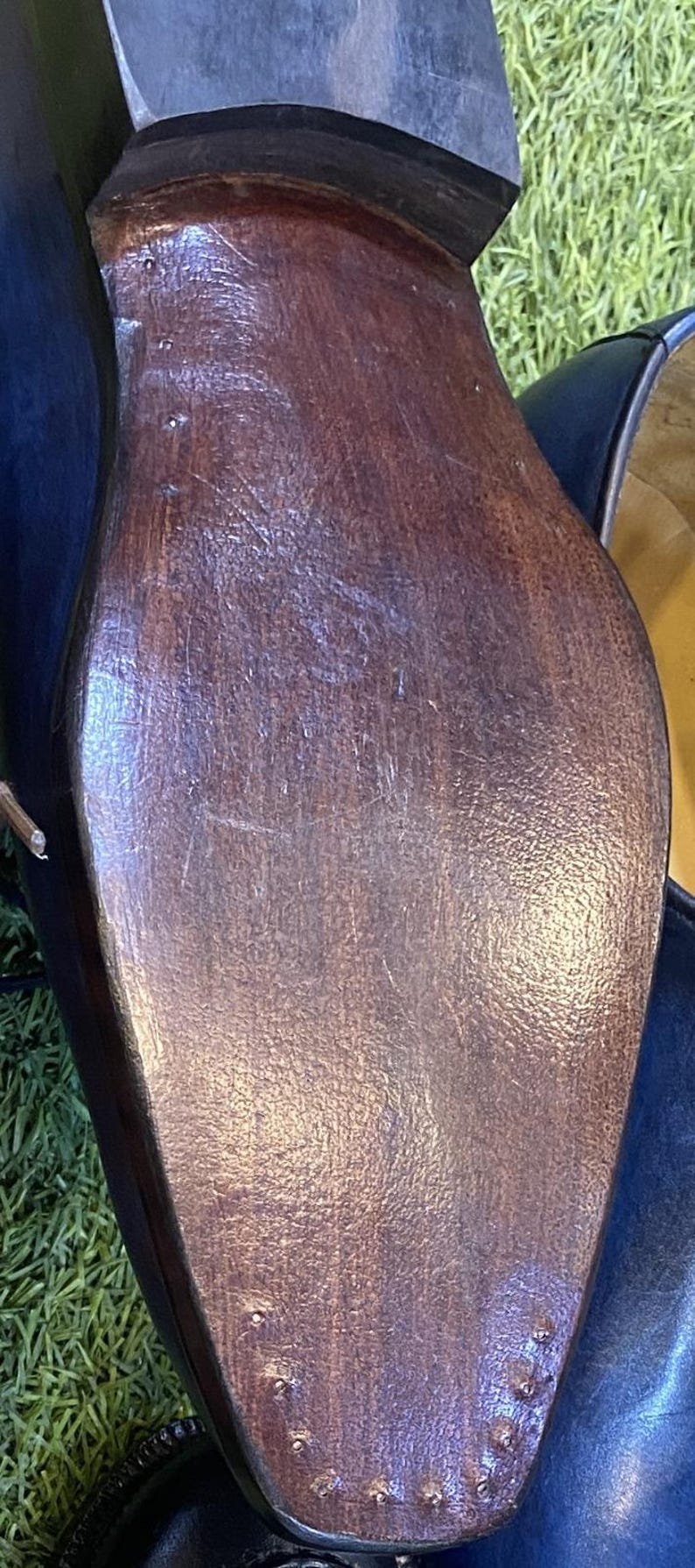 May include: The bottom sole of a dark brown leather shoe featuring a stacked heel and a smooth, polished finish. The sole is secured with a series of small, visible metal nails along the rounded toe and the arch, showing a classic construction.