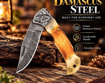 Può includere: Un coltello a serramanico con lama in acciaio Damasco dal motivo ondulato e manico di colore chiaro. La guardia è incisa con una testa d'aquila. Il testo sull'immagine recita: DAMASCUS STEEL, BUILT FOR EVERYDAY USE, Unique Damascus Pattern, Comfortable Handle, Everyday Utility.