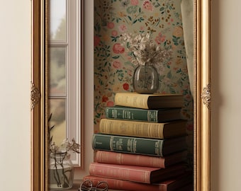Può includere: Uno specchio da parete rettangolare con una cornice dorata decorata. Il riflesso mostra una pila di sei libri con copertina rigida nei toni del verde, beige e rosso, un vaso di vetro con fiori secchi, un paio di occhiali e una carta da parati floreale.
