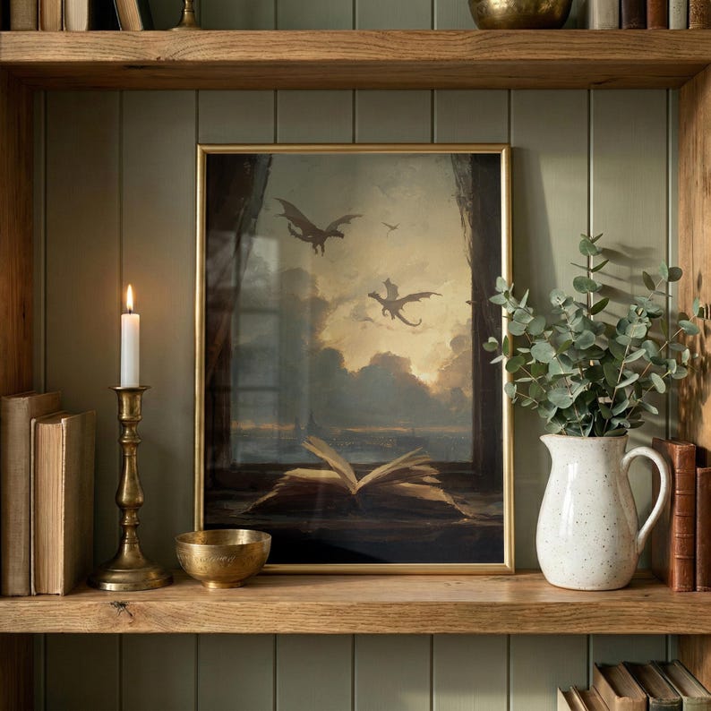 May include: A framed artwork depicting dragons soaring through a cloudy sky above an open book. The artwork is displayed on a wooden shelf with a lit candle in a brass holder, a small brass bowl, and a white pitcher with greenery.