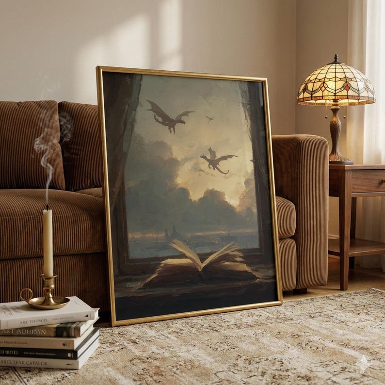 May include: A framed artwork depicts a fantasy scene with dragons soaring in a cloudy sky. An open book rests on a windowsill, with a view of the dragons and a distant cityscape. The artwork is in a gold frame.