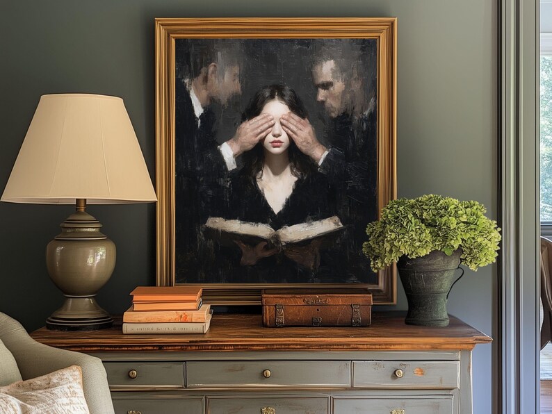 Puede incluir: Pintura al &oacute;leo enmarcada que representa a una mujer con los ojos cubiertos por dos hombres, sosteniendo un libro abierto. Una l&aacute;mpara, libros y una peque&ntilde;a caja est&aacute;n sobre una mesa de madera. Tambi&eacute;n hay un jarr&oacute;n con flores verdes.