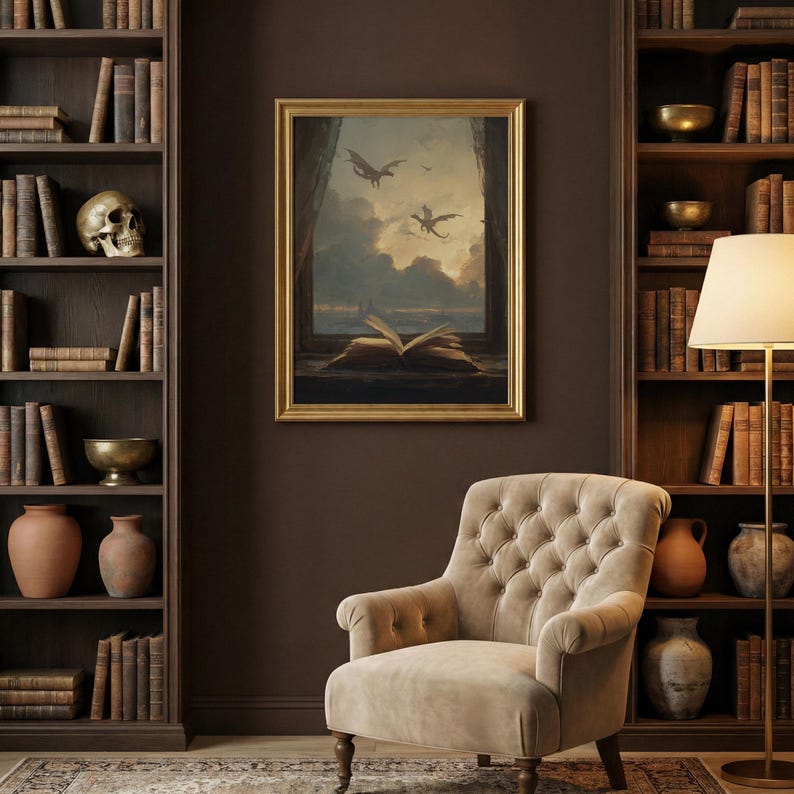 May include: A framed painting depicts dragons flying over a seascape with an open book on a windowsill. The painting is in a gold frame and hangs above a button-tufted armchair. Bookshelves filled with books and decorative items flank the painting.