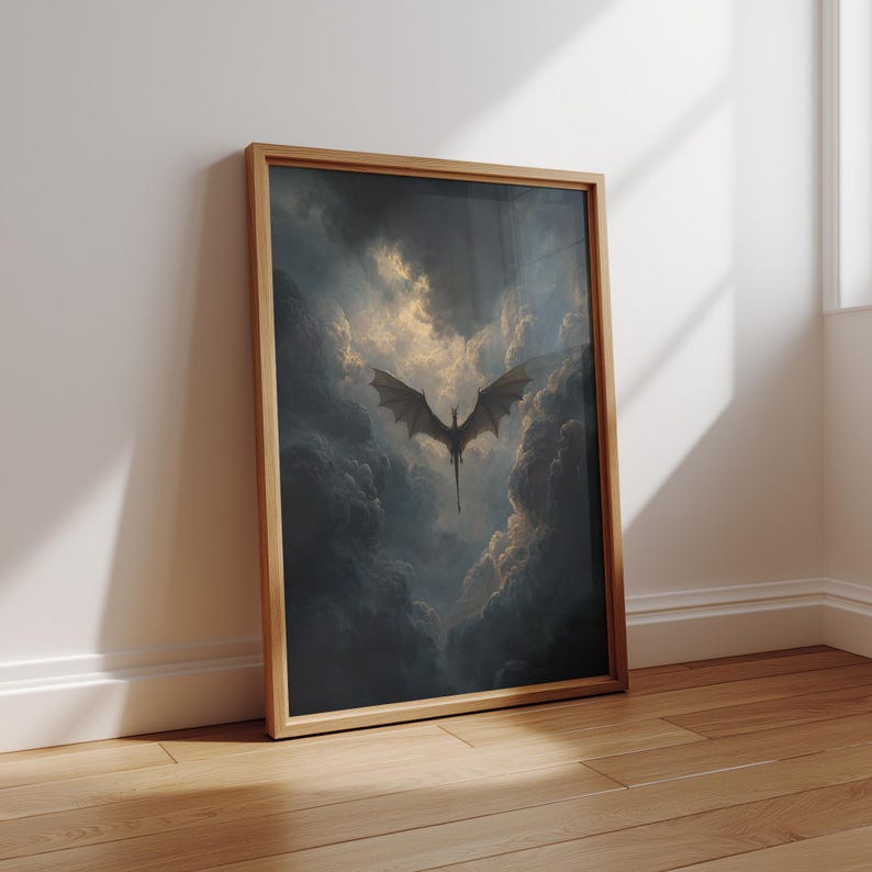 May include: A framed art print depicting a dragon in flight amidst a dramatic, cloudy sky. The dragon's silhouette is set against a bright, golden light, with dark, ominous clouds. The frame is light brown, and the artwork leans against a white wall.