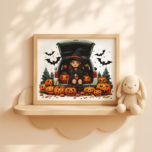Op de afbeelding: Een ingelijste Halloween-illustratie met een jonge heks die in de open kofferbak van een auto zit, omringd door uitgesneden pompoenen. Zwarte vleermuizen en groene bomen op de achtergrond. Een pluchen konijn zit op een plank.