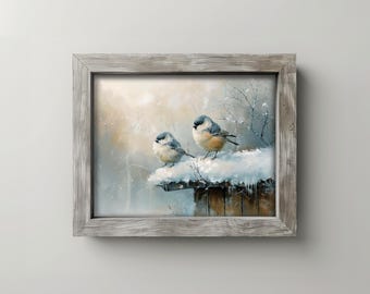 May include: A framed painting shows two small birds with grey and tan plumage, perched on a snow-covered wooden structure. The background is a soft, blurred winter scene with muted colours and a light snowfall. The frame is made of weathered wood.