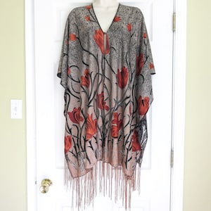 May include: A gray and brown poncho with a floral pattern featuring red and orange tulips. The poncho has a fringe trim.