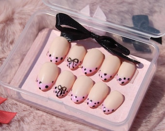 Uñas postizas de lunares negros y rosas con lazos para fiesta de verano