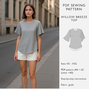 Könnte beinhalten: Eine Frau trägt ein hellgraues Willow Breeze Top mit kurzen Ärmeln und weißen Shorts. Das Oberteil hat einen runden Ausschnitt und einen leicht gebogenen Saum. Der Text lautet "PDF Sewing Pattern Willow Breeze Top" und "Größen XS - XXL".