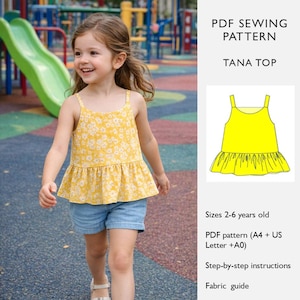 May include: A young girl wearing a yellow floral print tank top with a ruffled hem and denim shorts. The tank top has thin straps. The image also includes a graphic of the Tana Top pattern and text that reads "PDF Sewing Pattern Tana Top".