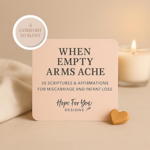 May include: A light pink card with rounded corners, bearing the text "WHEN EMPTY ARMS ACHE" and "30 SCRIPTURES & AFFIRMATIONS FOR MISCARRIAGE AND INFANT LOSS." A small wooden heart and a lit candle are also visible.