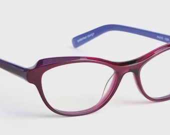 May include: A pair of cat-eye eyeglasses with a deep purple frame and blue temples. The glasses have a sleek, modern design with clear lenses. The text "patented design" is printed on the blue temple.