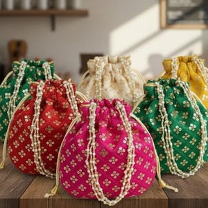 May include: A collection of drawstring pouches in various colors, including green, red, pink, yellow, and cream. Each pouch features a floral pattern and is adorned with a beaded trim. The pouches are arranged on a wooden surface.