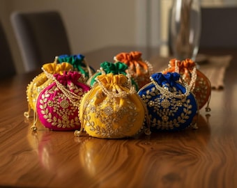 May include: A collection of colorful, embroidered drawstring pouches in various shades, including pink, yellow, blue, green, and orange. Each pouch features intricate gold-colored embroidery and beaded accents, resting on a wooden surface.