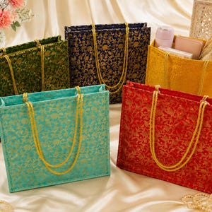 Peut inclure: Un ensemble de cinq sacs fourre-tout rectangulaires en vert, bleu foncé, jaune, turquoise et rouge, chacun orné d'un motif floral brocart doré et de deux anses en corde tressée dorée. Le sac jaune contient une petite bouteille, un portefeuille et une pochette.
